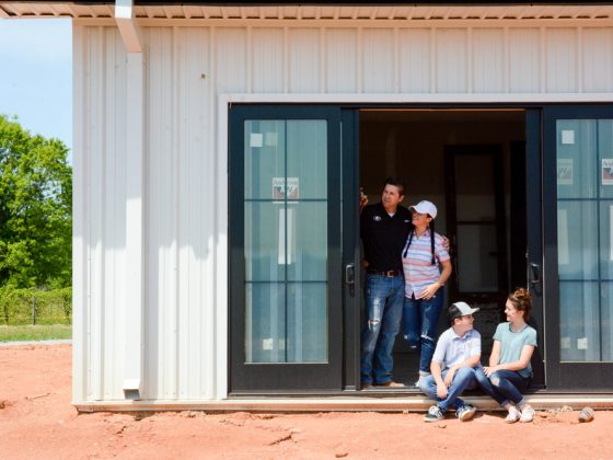 The Busentiz Family in front of their steel-framed farmhouse