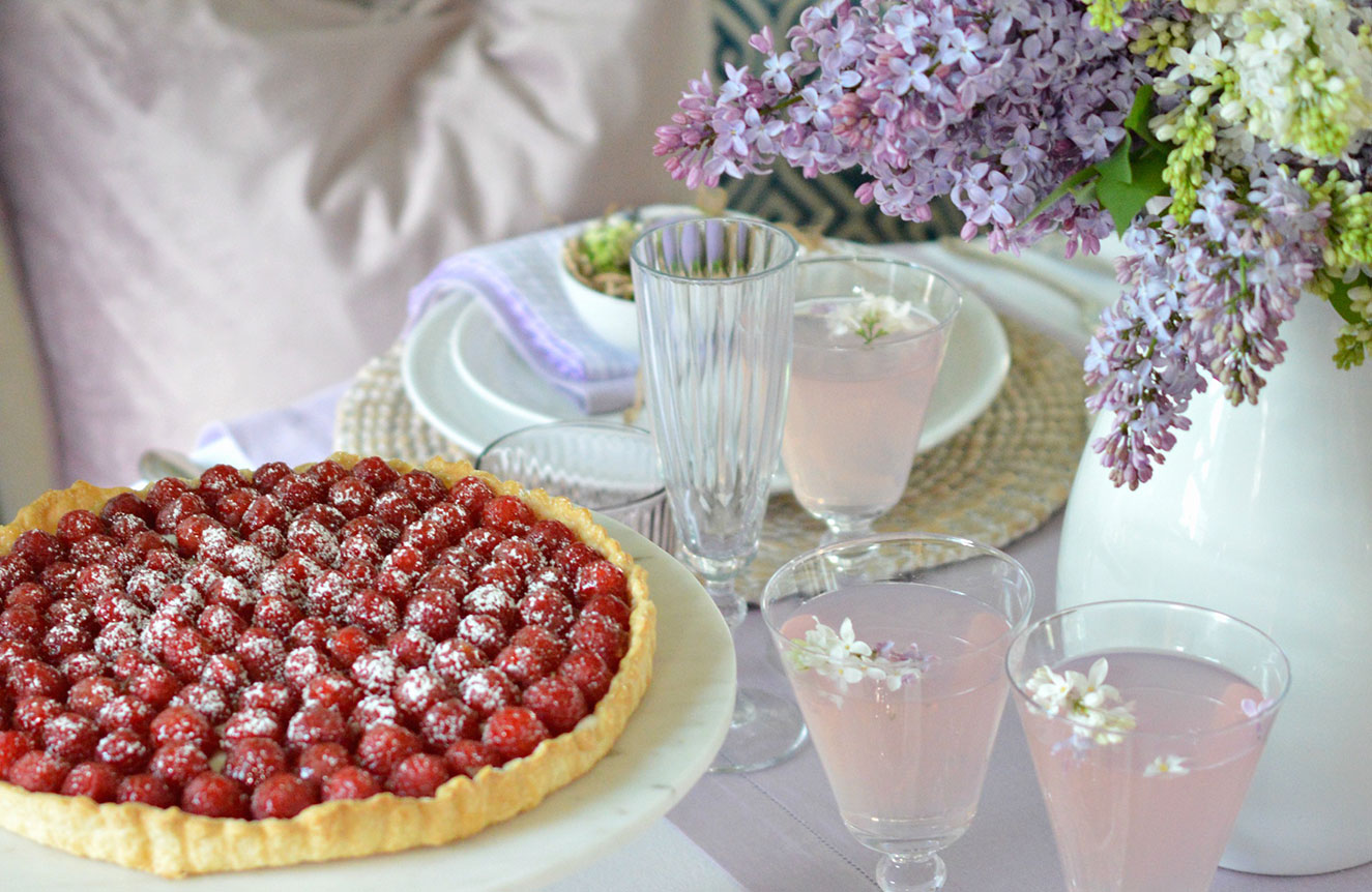 raspberry tart and pink lemonade on a pretty table with lilacs