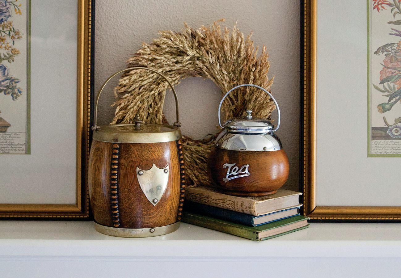 Wooden biscuit barrels placed on a stack of books and displayed in front of a wreath.