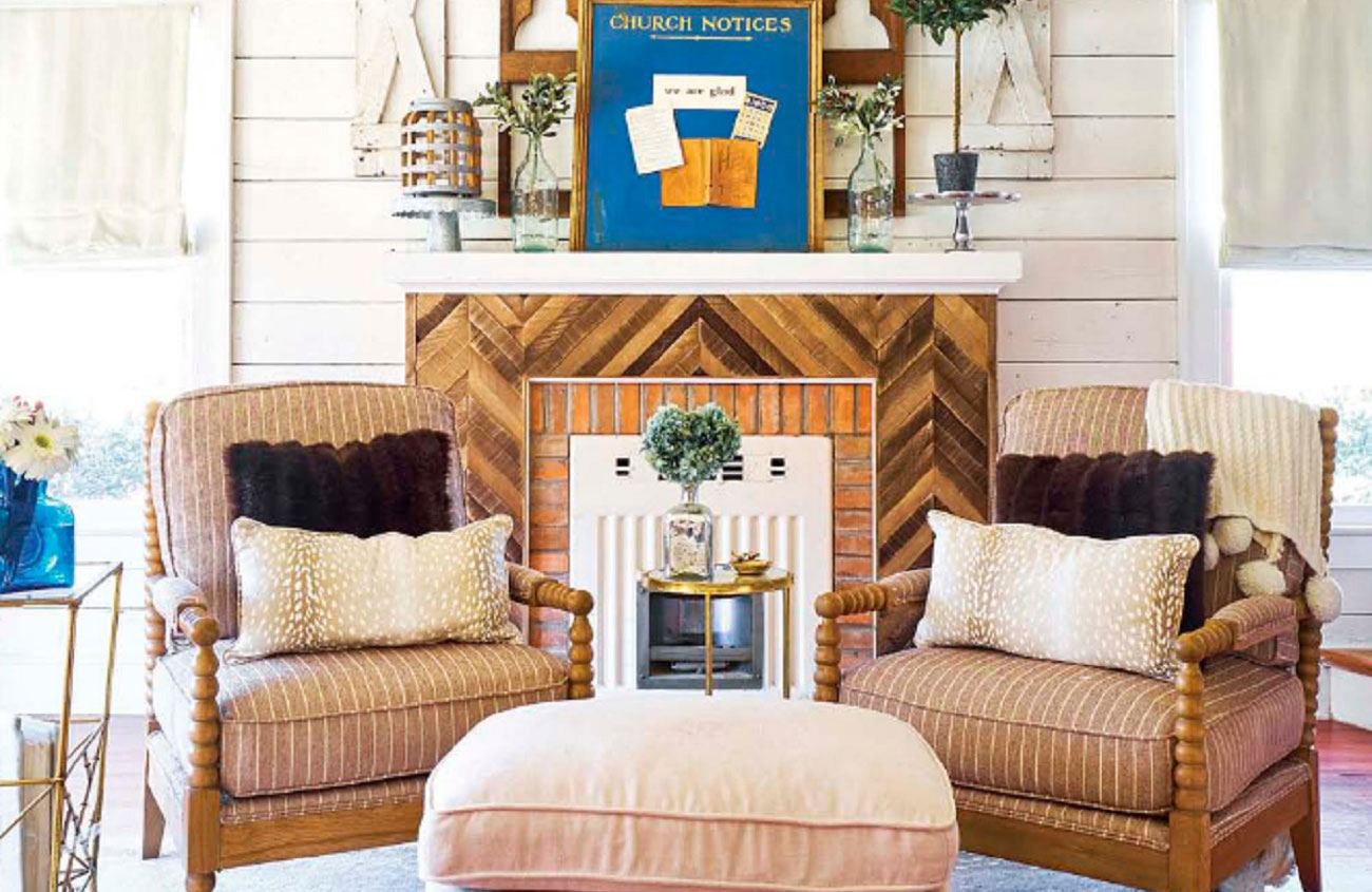 Living room with 2 armchairs and a restored shiplap and brick fireplace.