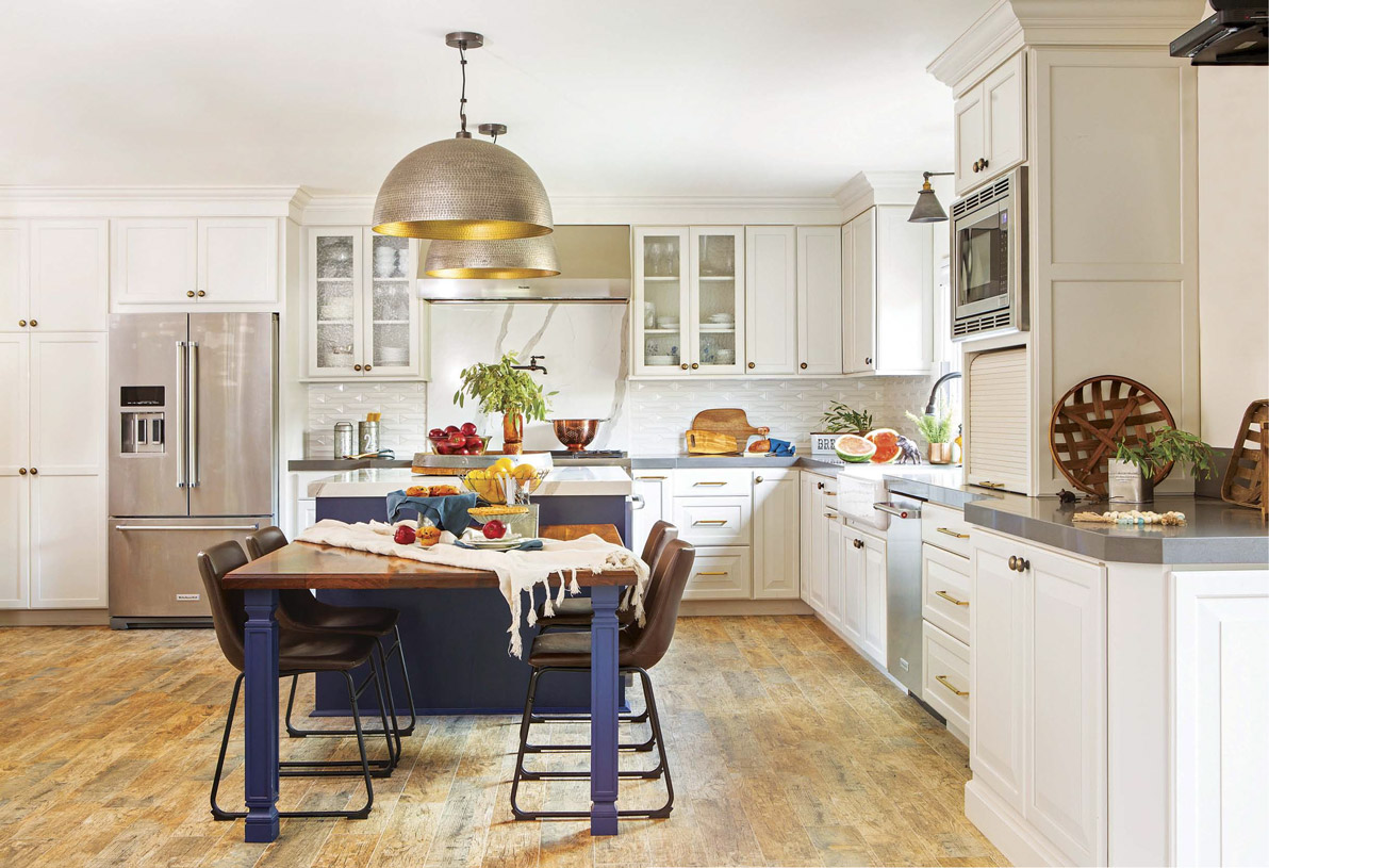White custom kitchen with dome pendant lights and navy blue and wooden kitchen table.