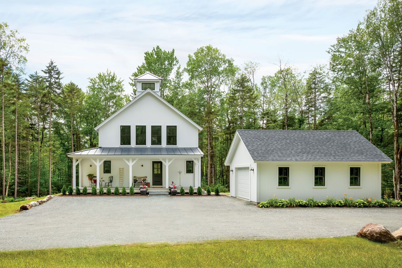 Exterior shot of a traditional farmhouse with a gabled porch and a detached garage.