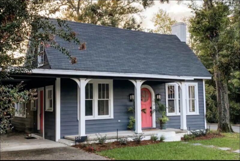 Cottage on Fort exterior with blue siding and pink door with rounded window